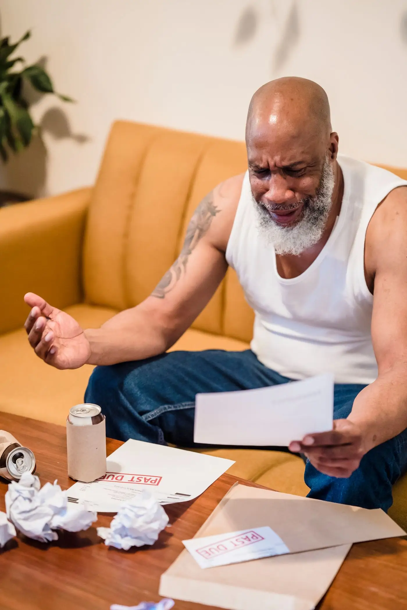 Man on a sofa looking stressed while reviewing bills