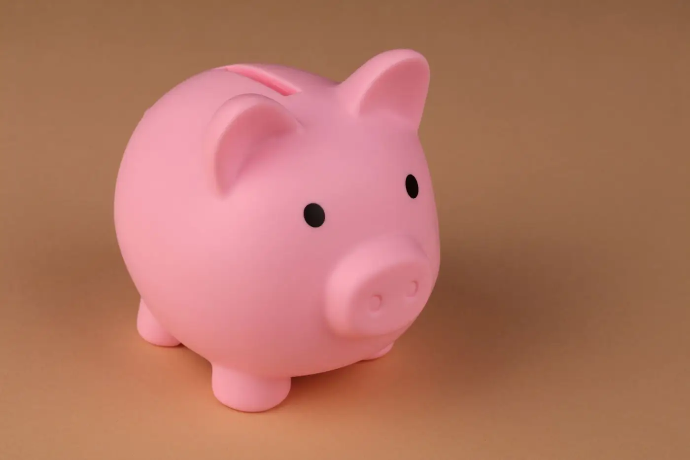 Pink piggy bank on a warm peach background
