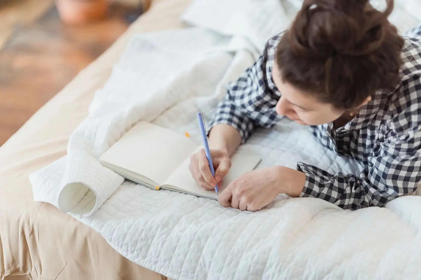 Woman lying on her bed writing in a journal
