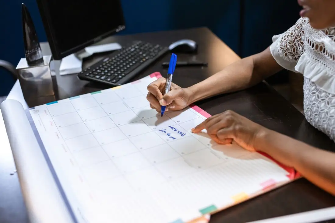 A person writing payoff milestones in a large wall planner calendar