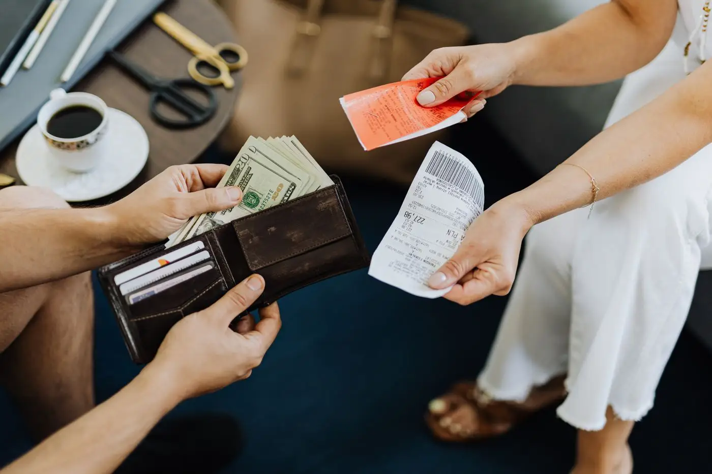 Two people reviewing receipts beside an open wallet and a cup of coffee