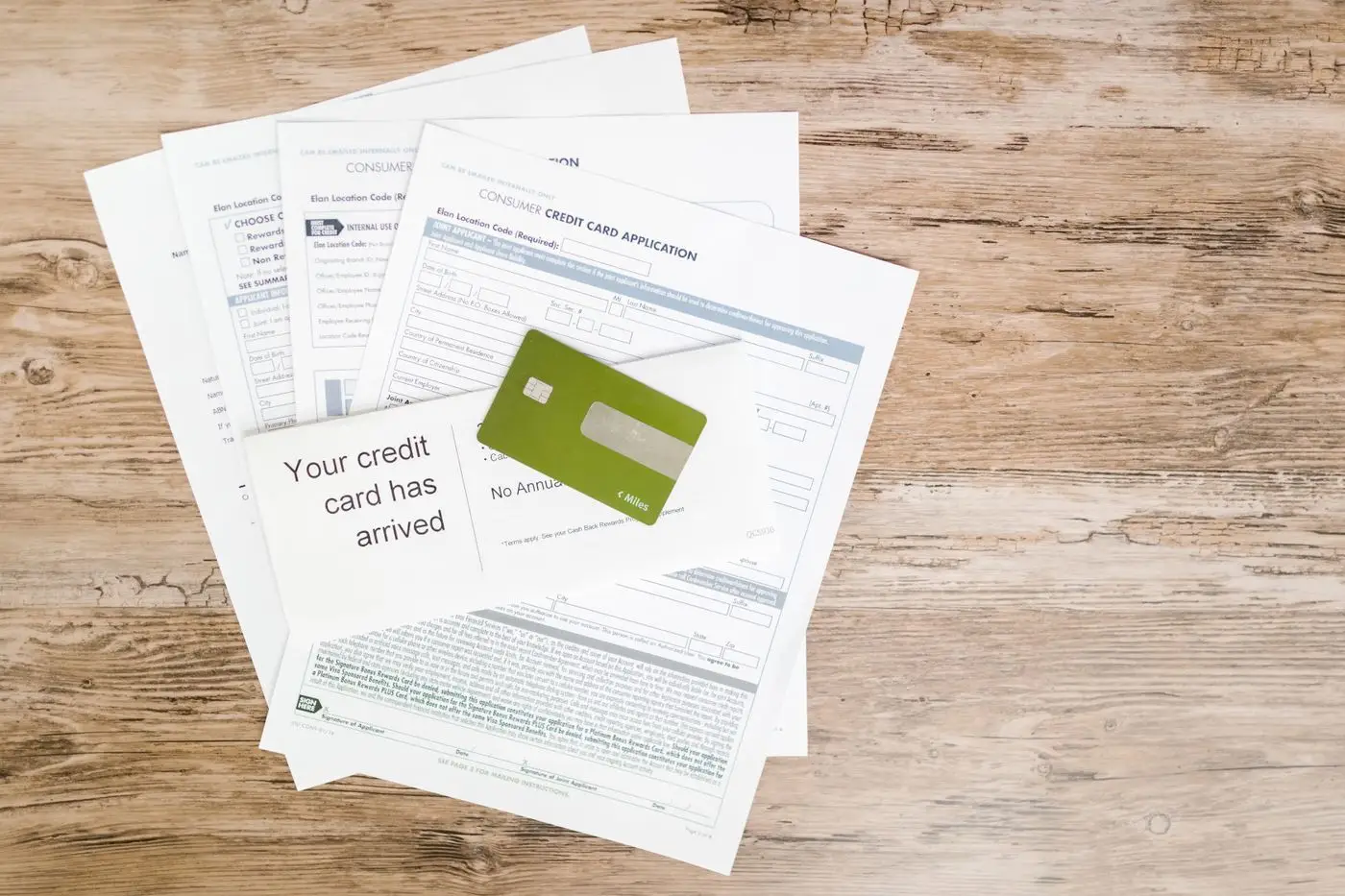 Credit card statements and a bank card spread across a wooden table